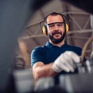 Factory worker operating band saw cutting machine for steel bars in the industrial factory